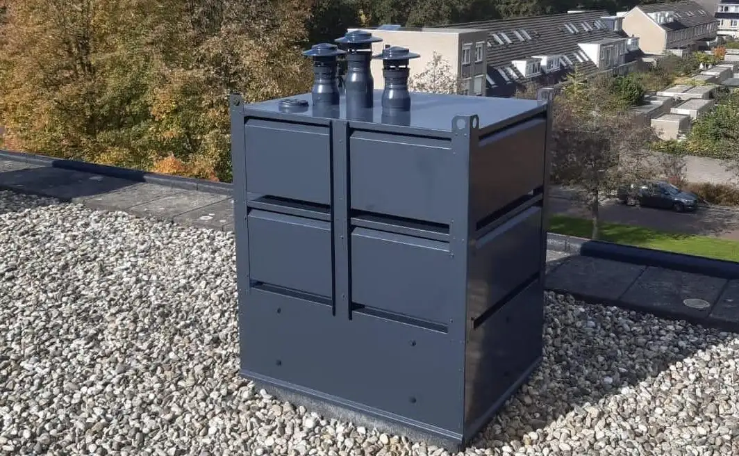 Donkergrijze prefab schoorsteenunit met drie concentrische rookgasafvoeren op een plat grinddak, ideaal voor renovatieprojecten.